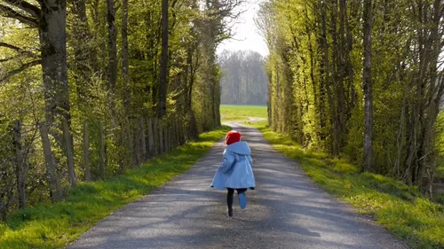 Une petite fille qui cour sur un chemin autour d'une forêt