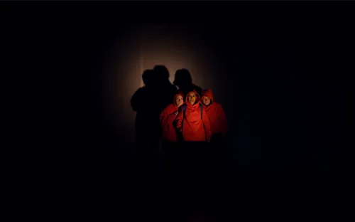 Trois personnes dans la pénombre avec des sweatshirts rouges
